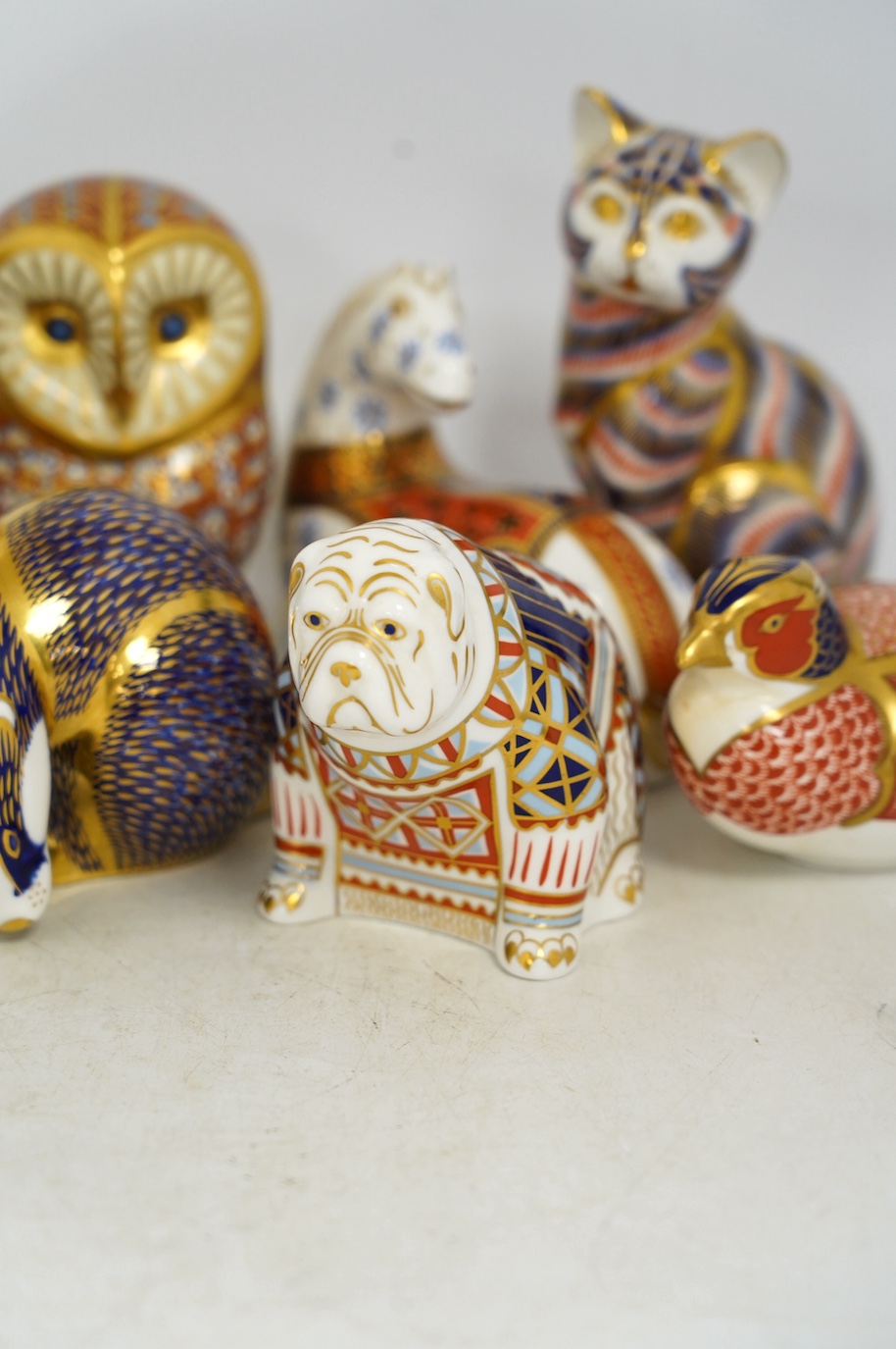 Eight Royal Crown Derby porcelain paperweights in the form of animals including a cat, badger and owl, largest 13.5cm high. Condition - good